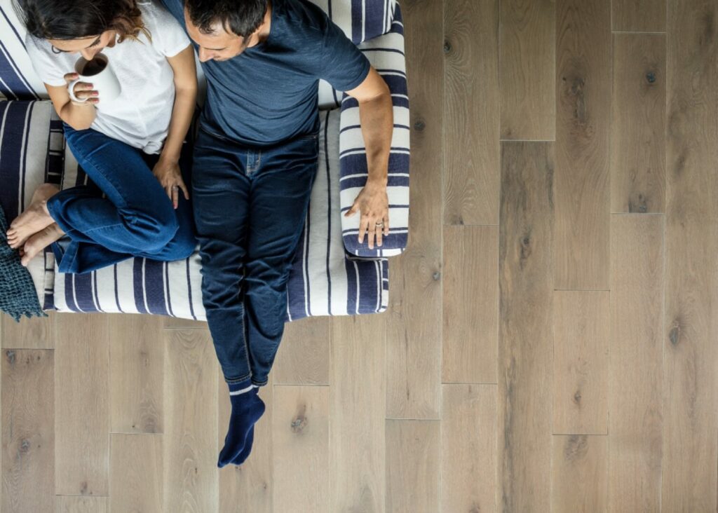Happy couple sitting on sofa | Tom's Carpet & Flooring Outlet